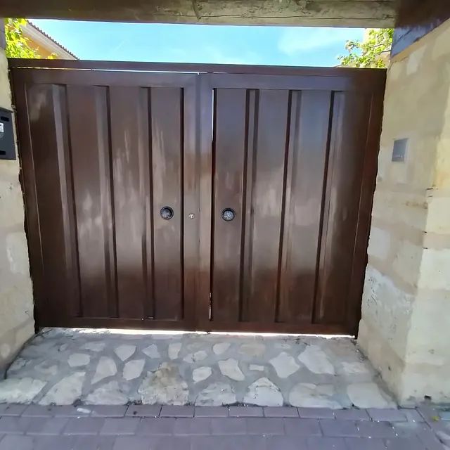 Una puerta marrón se abre a una pasarela de piedra.