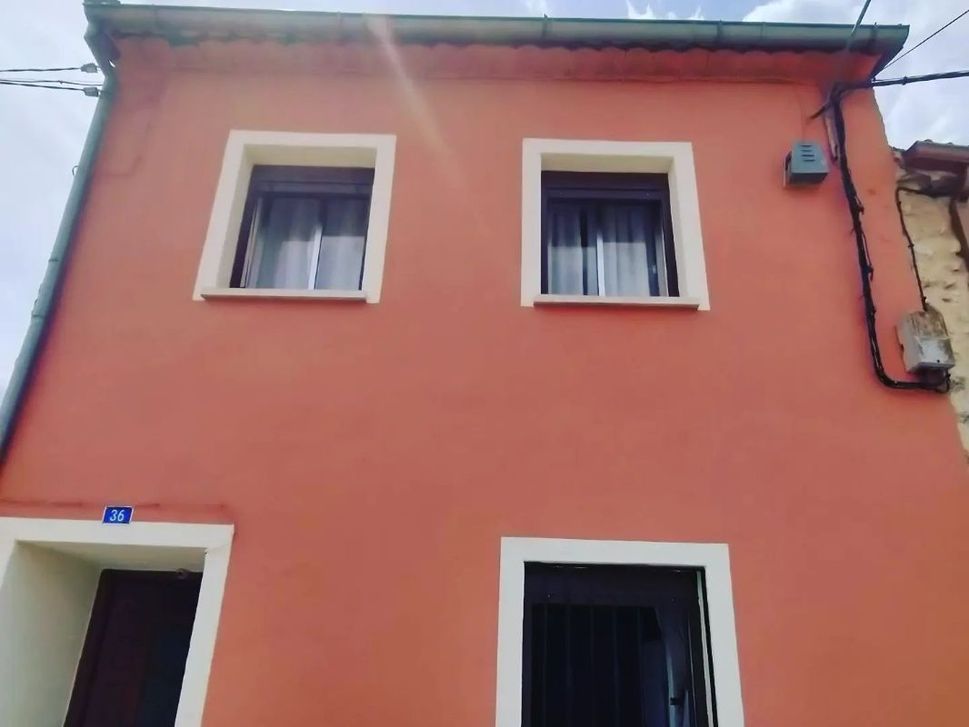 Una casa roja con molduras blancas y dos ventanas