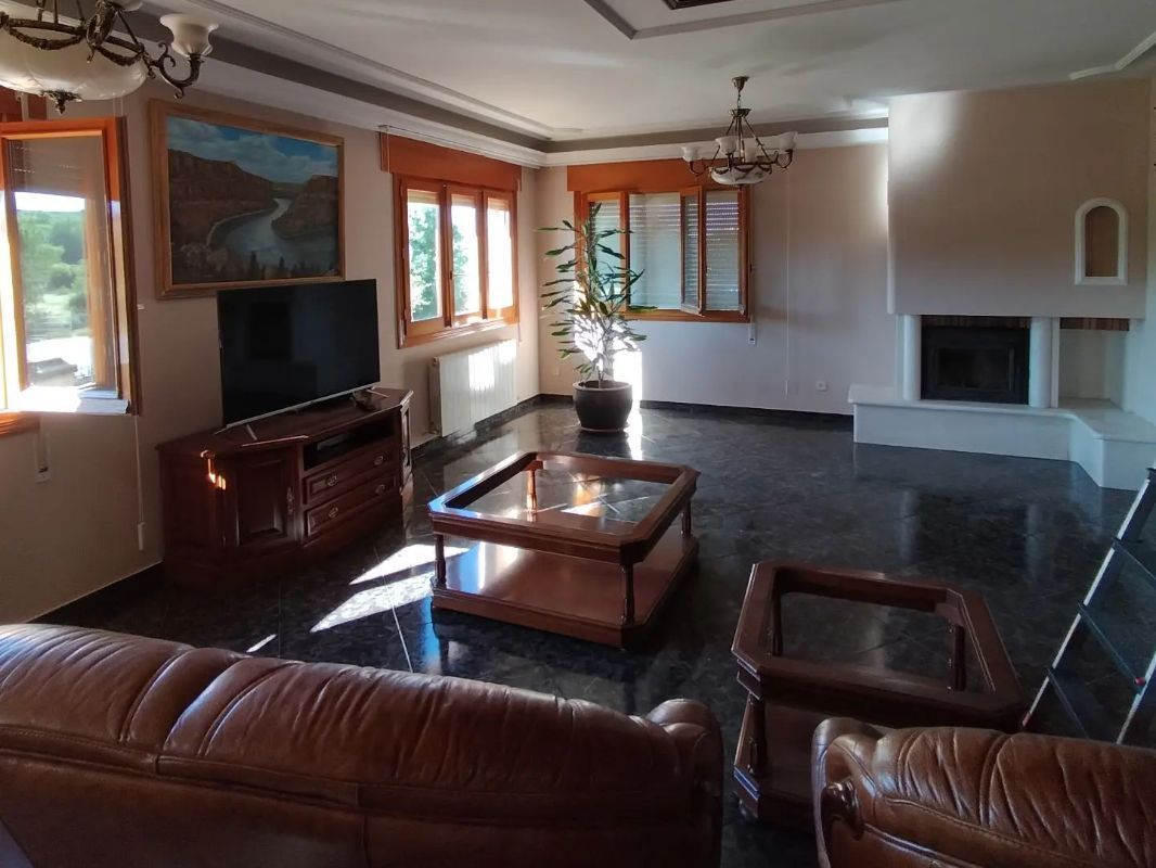 Una sala de estar con un sofá, un televisor y una chimenea.