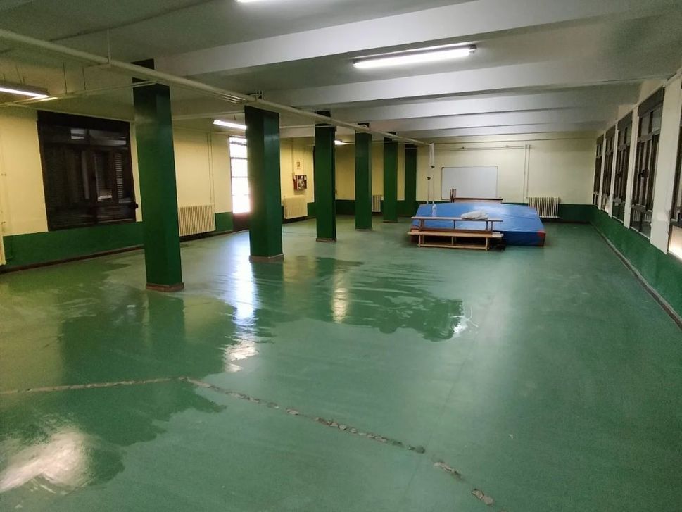 Una gran habitación vacía con suelos y columnas verdes.