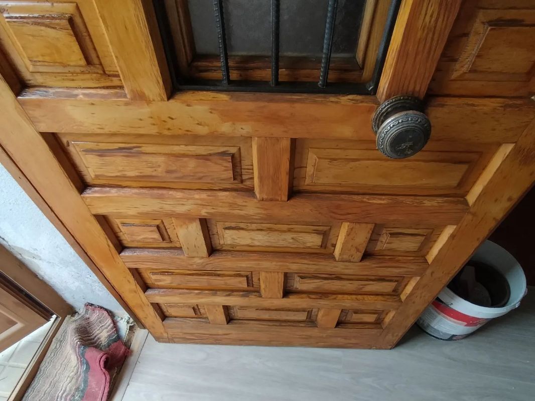 Una puerta de madera con manija de metal y una ventana de vidrio.
