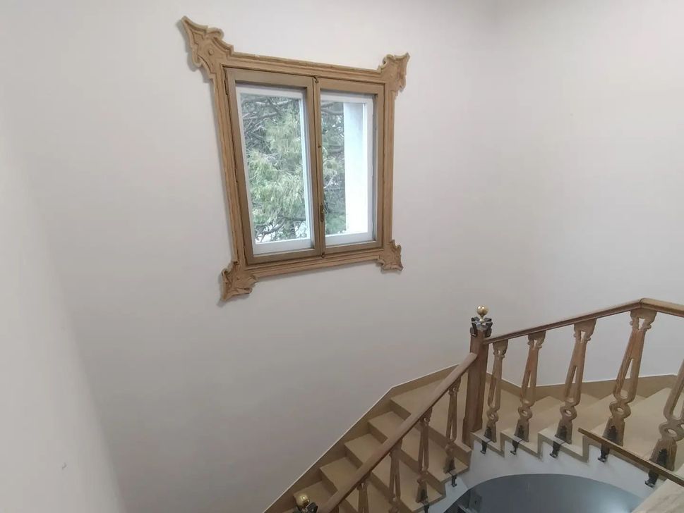 Una escalera con barandilla de madera y una ventana en la pared.