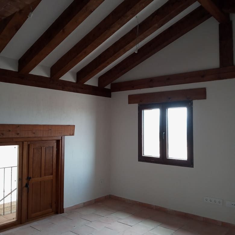 Una habitación vacía con techo de madera y dos ventanas.