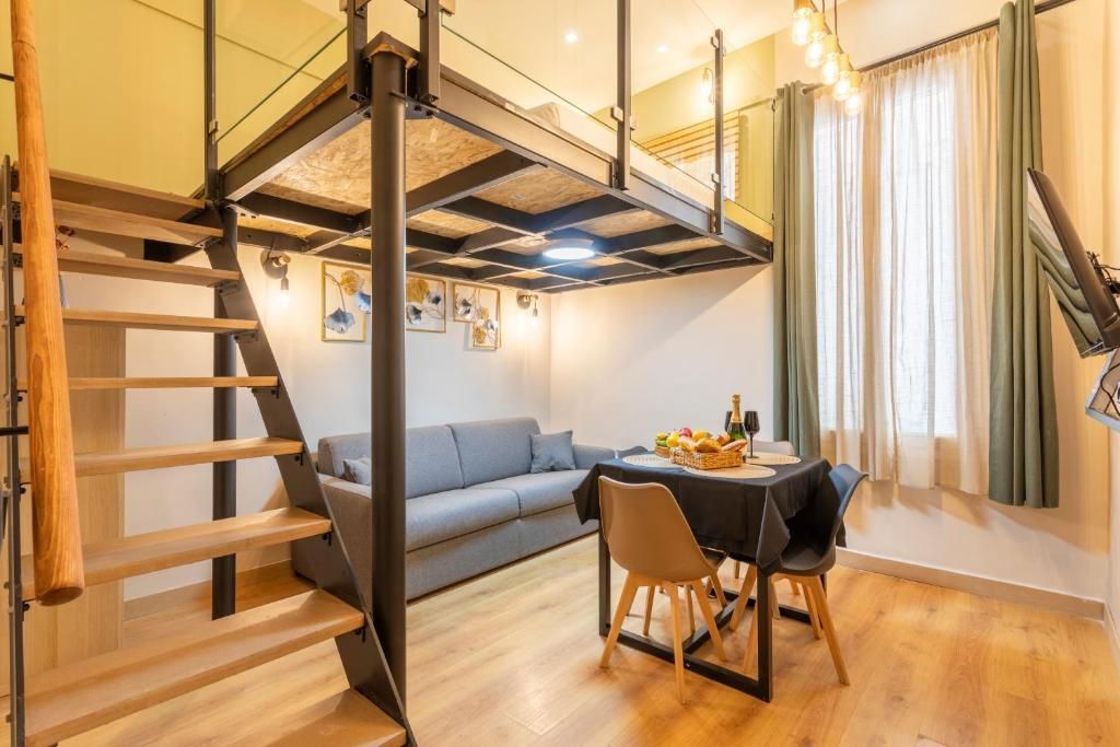 Un salon avec un canapé, une table et des chaises et un escalier menant au deuxième étage.