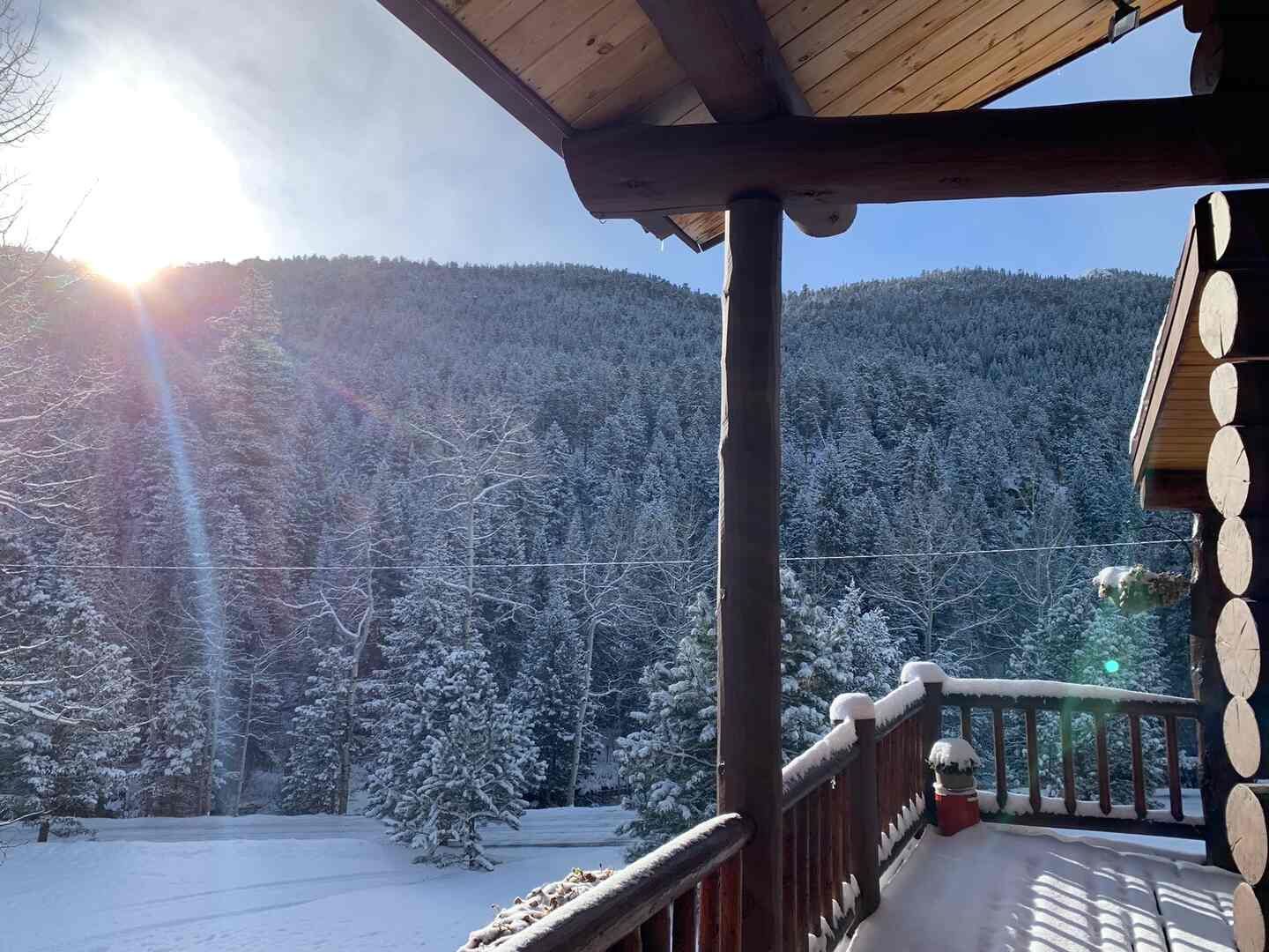 Winter sunrise over snowy pines from the deck at The Riverside Cabin in Allenspark, Colorado