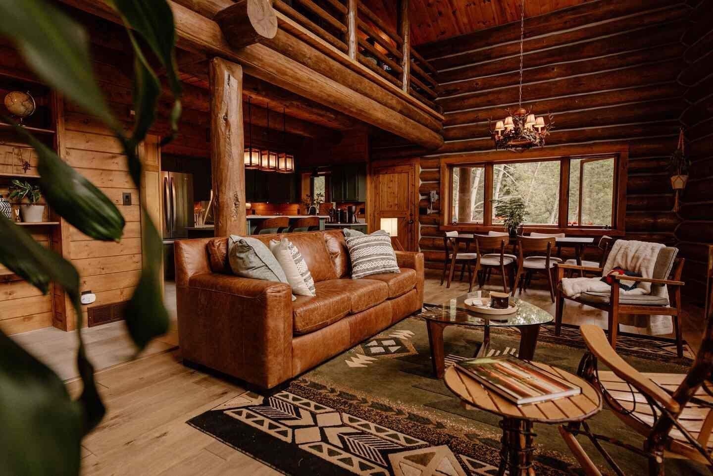 Great room seating area with leather sofa and antler chandelier inside The Riverside Cabin