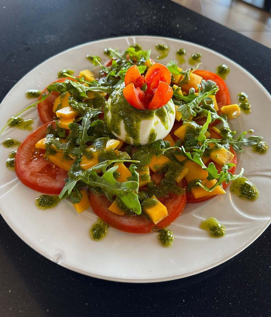 Un plato blanco cubierto con verduras y una flor encima.