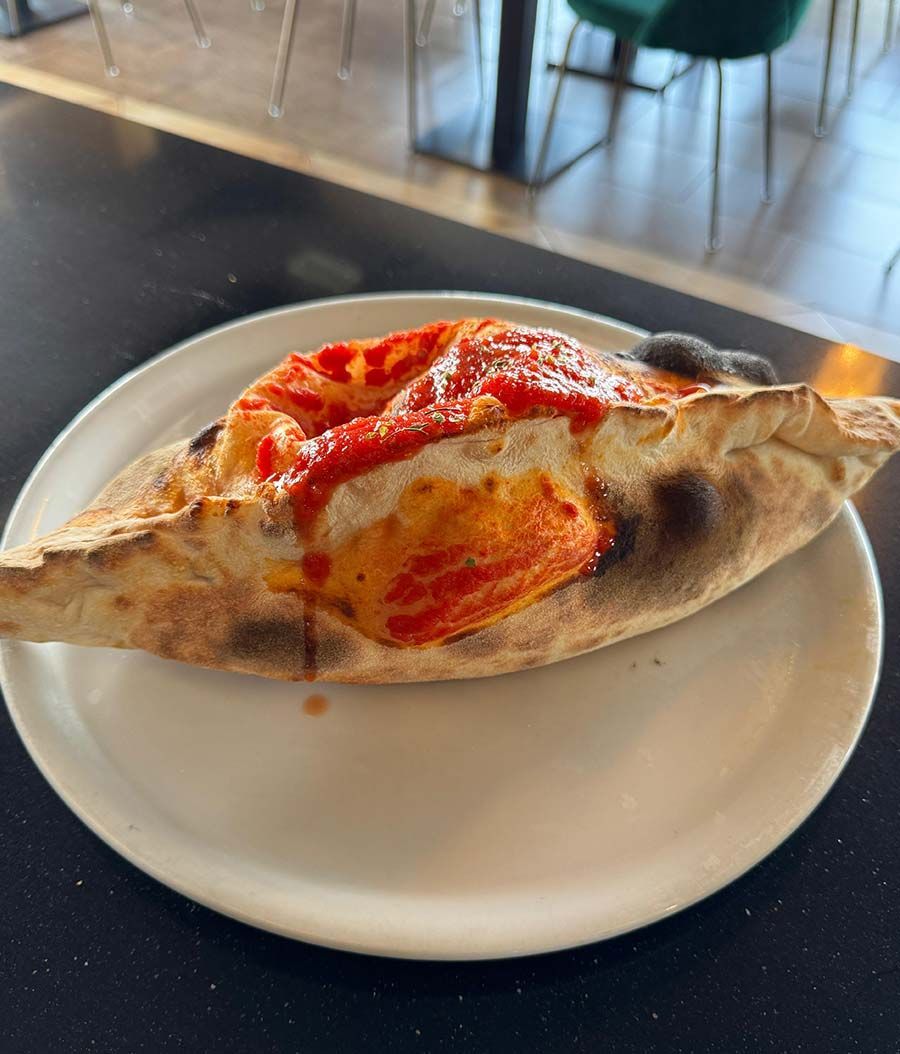 Un plato blanco con una porción de pizza encima.