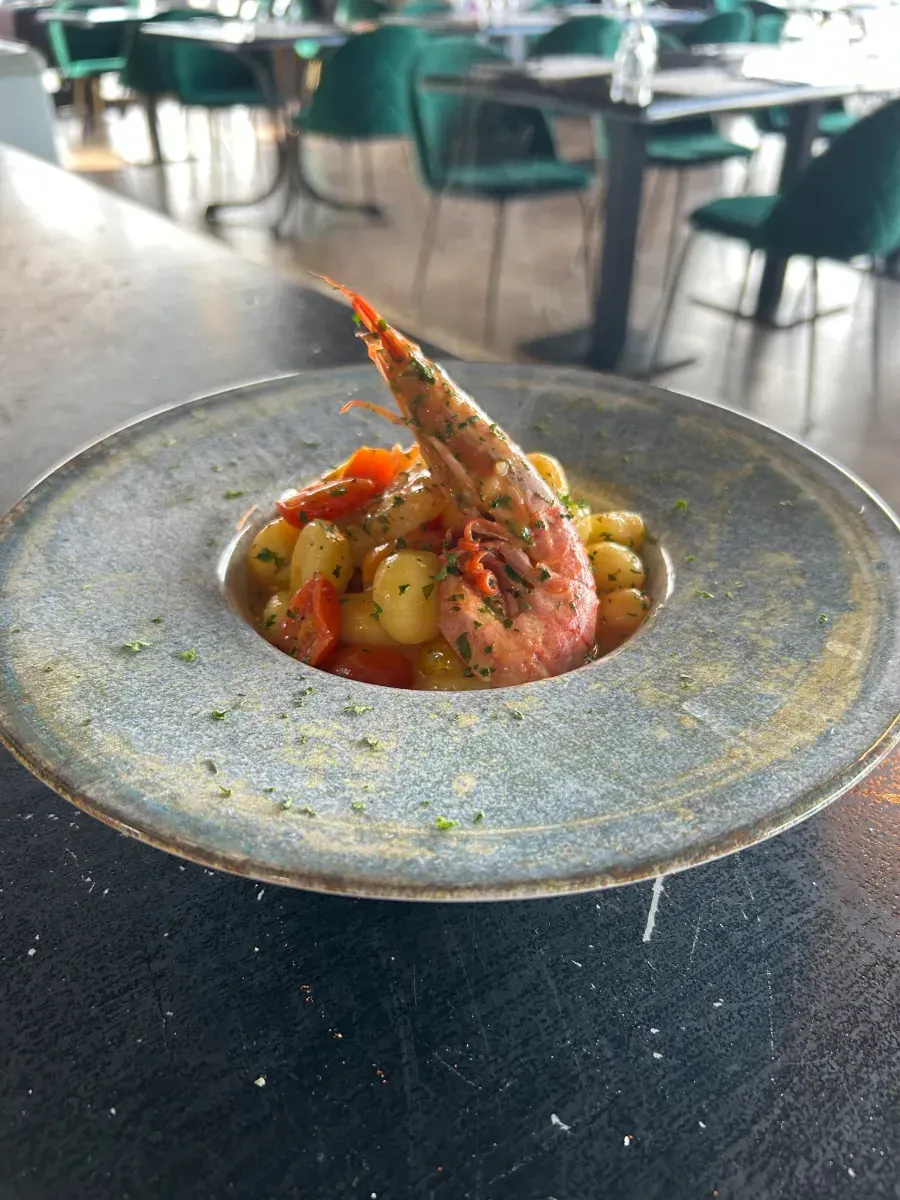 Un plato de comida con camarones y ñoquis en una mesa de un restaurante.