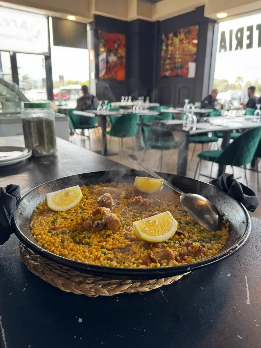 Una sartén de paella con rodajas de limón sobre una mesa en un restaurante.