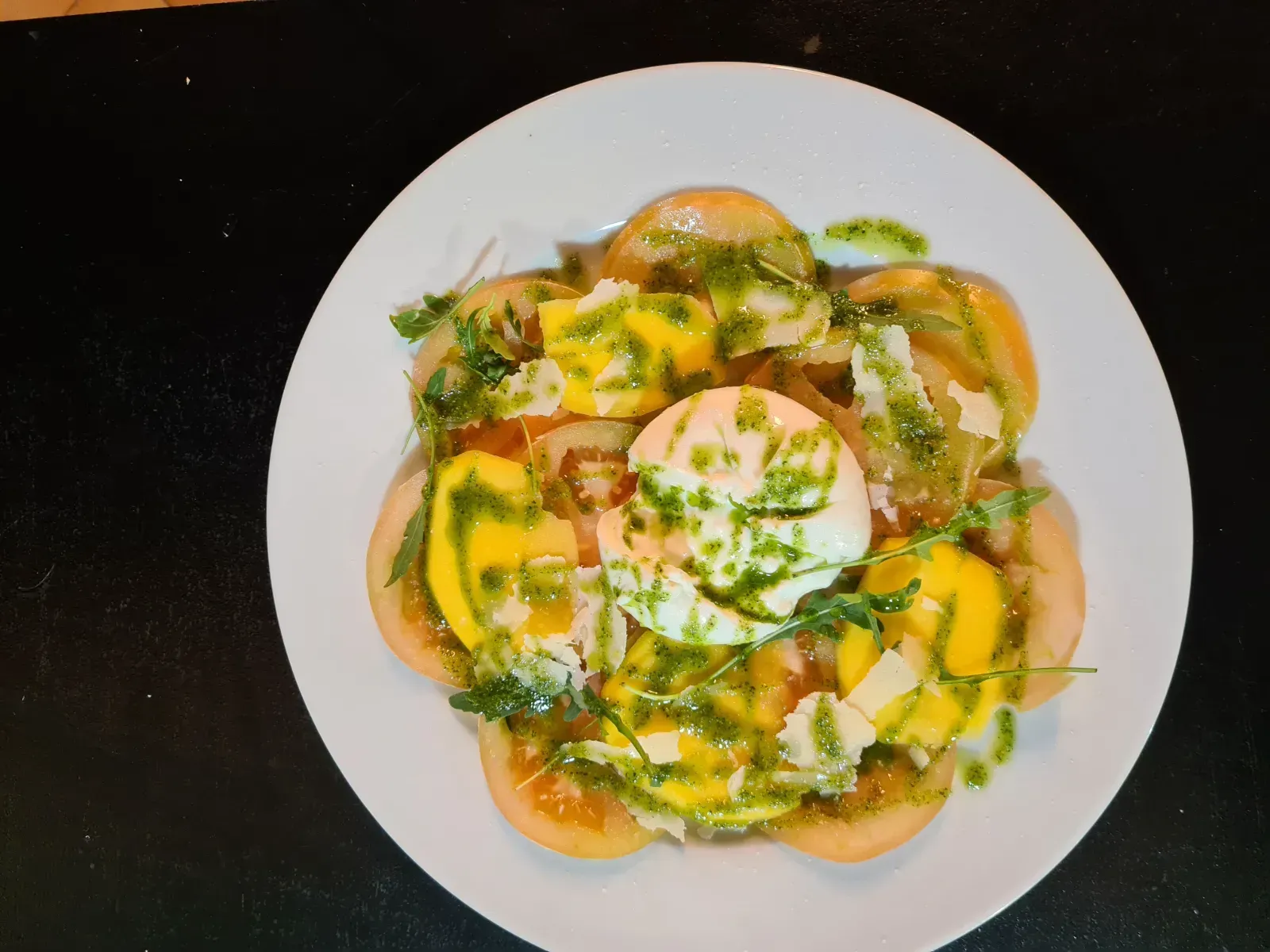 Un plato blanco cubierto con tomates y un huevo escalfado.