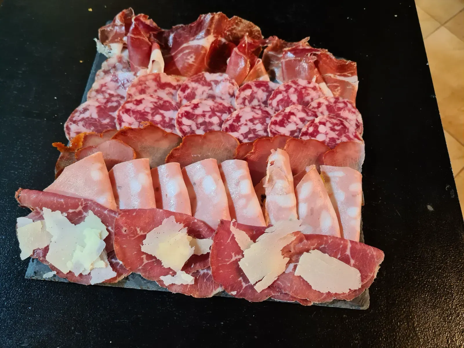 Una variedad de carnes en un plato negro sobre una mesa.