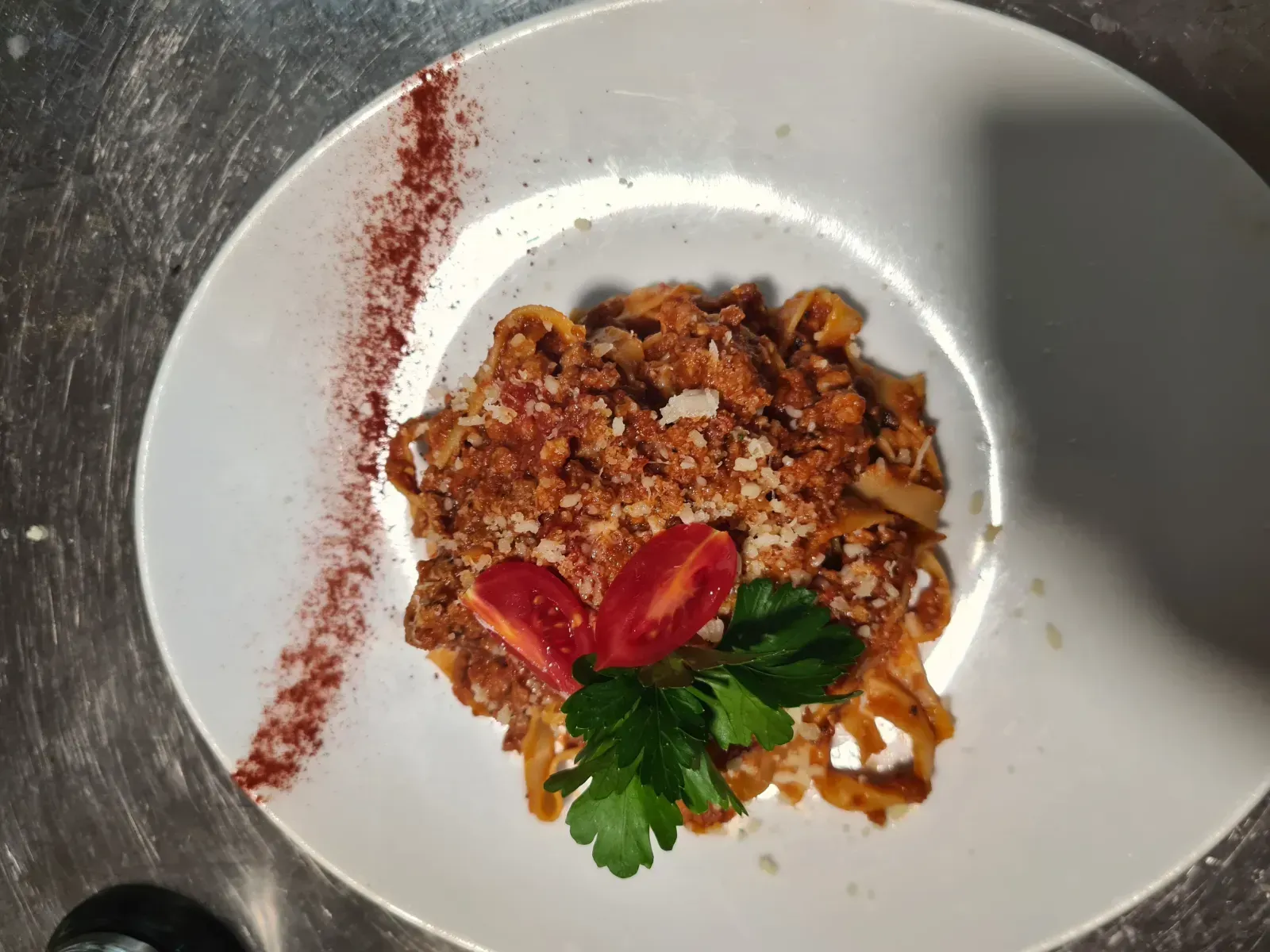 Un plato de pasta con tomates y perejil sobre una mesa.