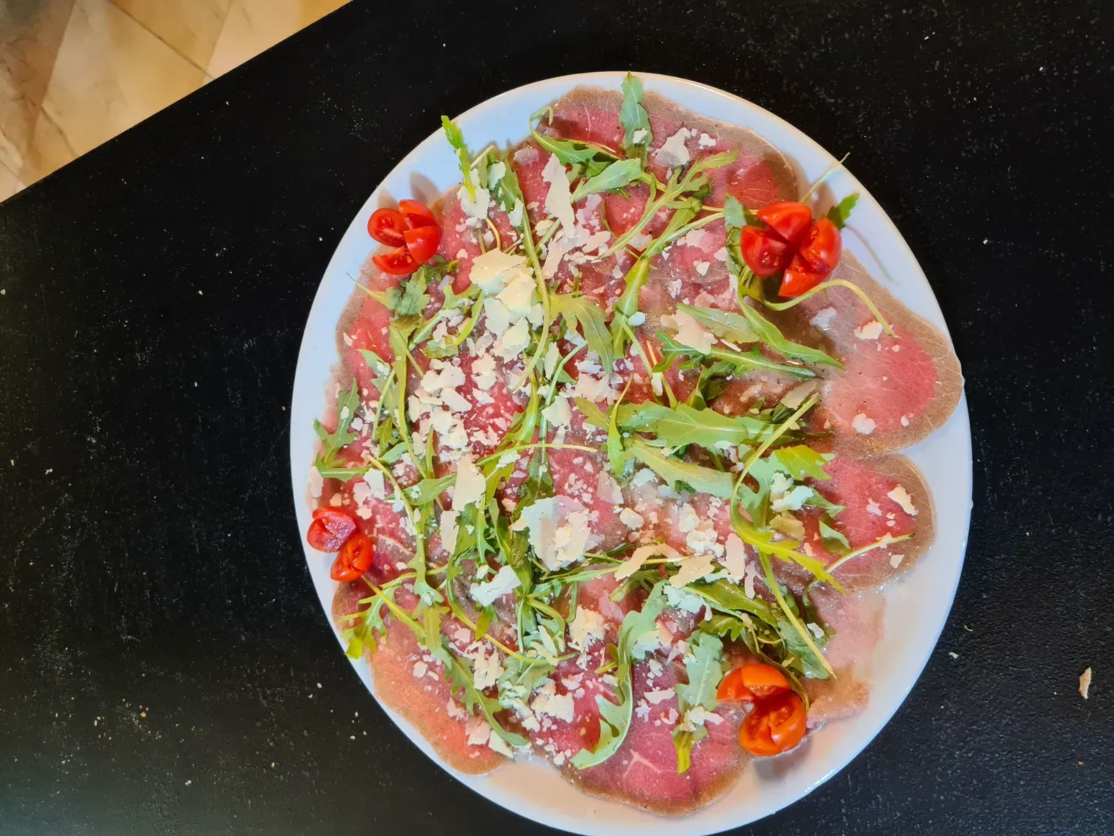 Un plato blanco cubierto con carne y verduras sobre una mesa.