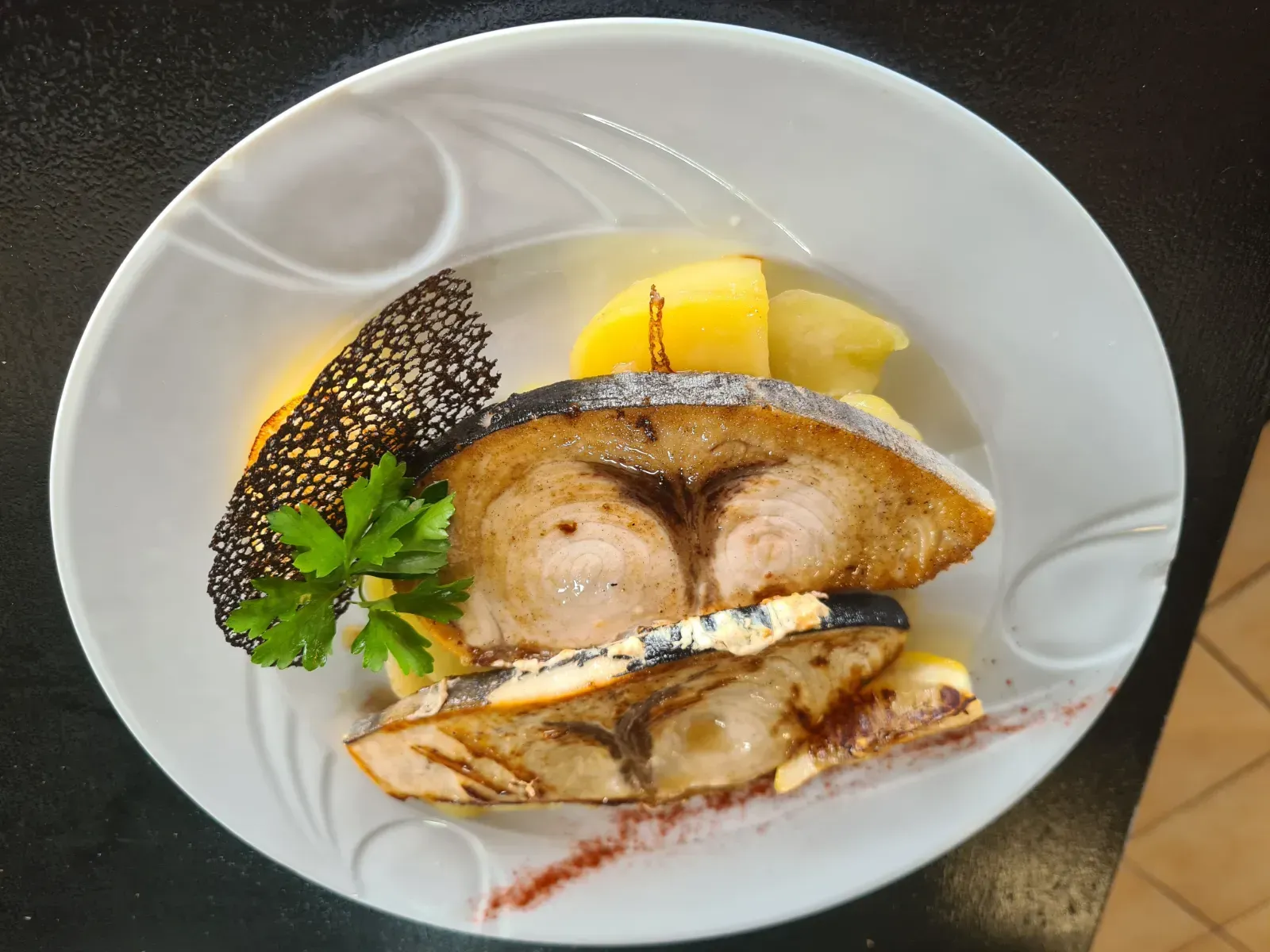 Un plato blanco cubierto con carne y patatas sobre una mesa.