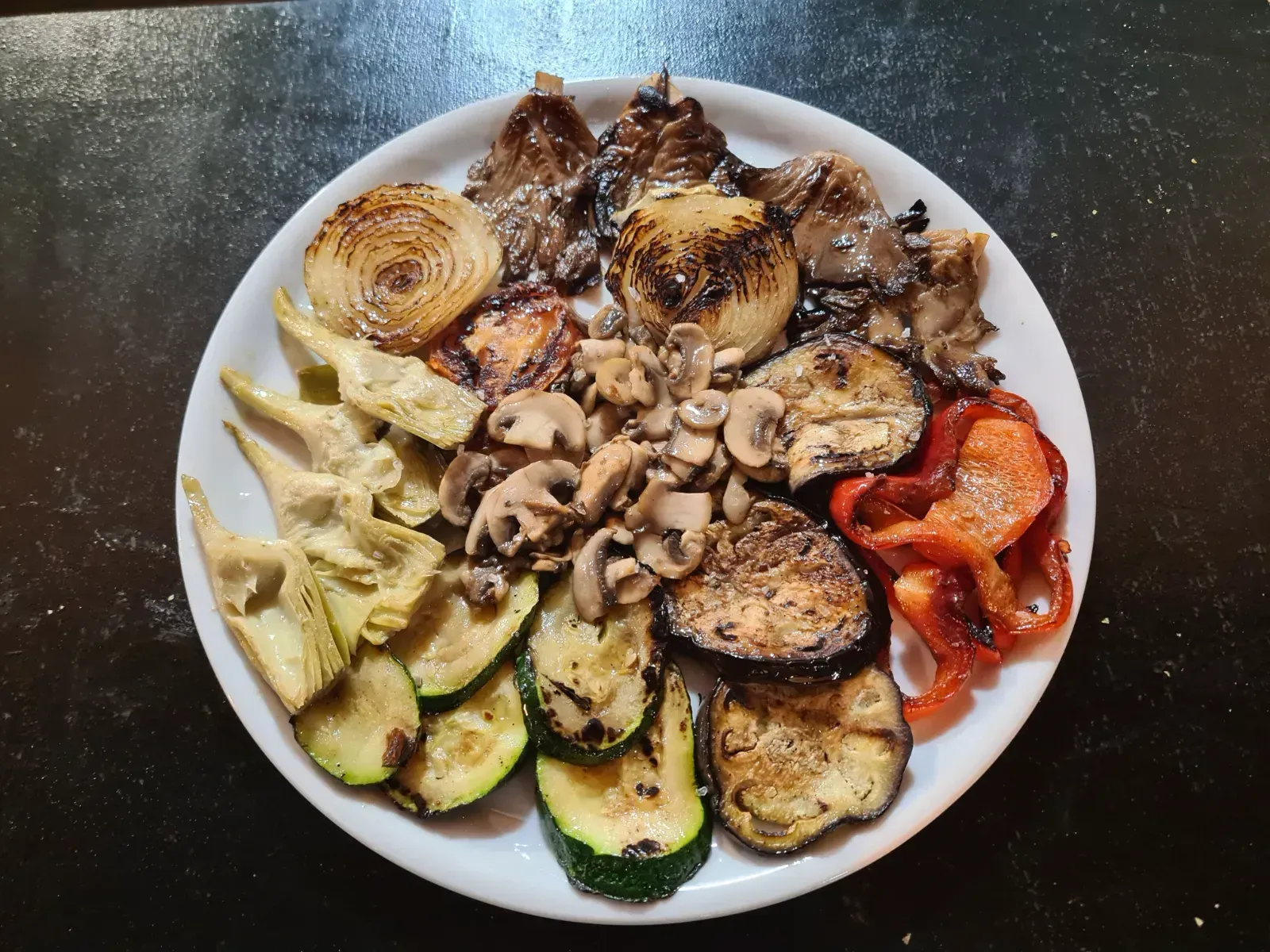 Un plato blanco cubierto con una variedad de verduras a la parrilla.