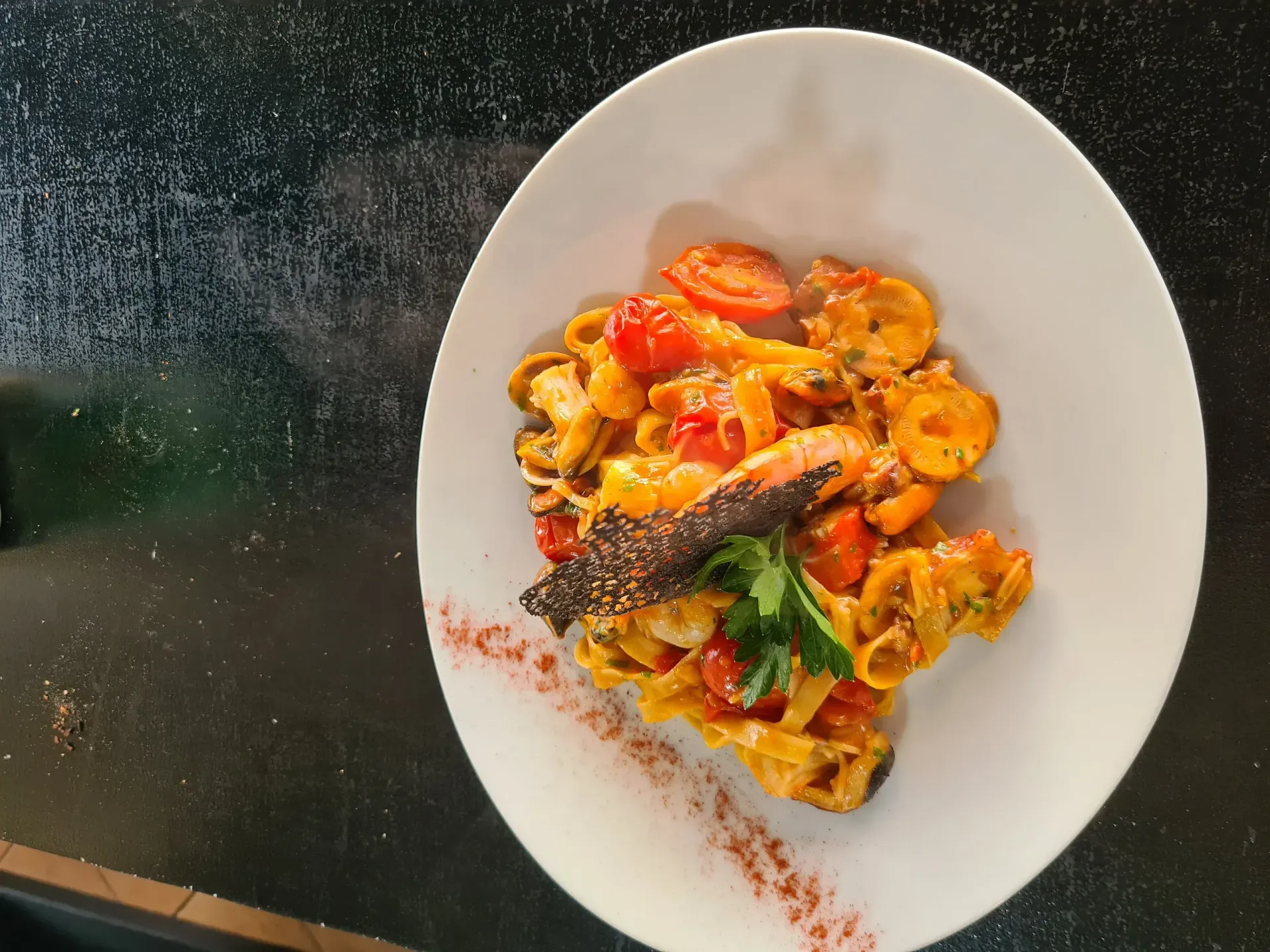 Un recipiente blanco lleno de pasta y tomates sobre una mesa.