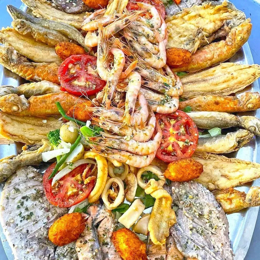 Gran plato de mariscos fritos: camarones, filetes de pescado, calamares, tomates y croquetas.
