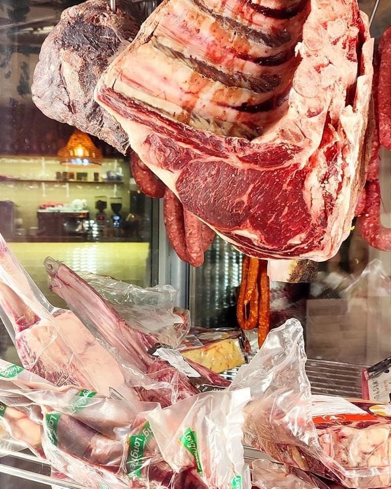 Trozos de carne cruda colgados y expuestos en el escaparate de una carnicería.