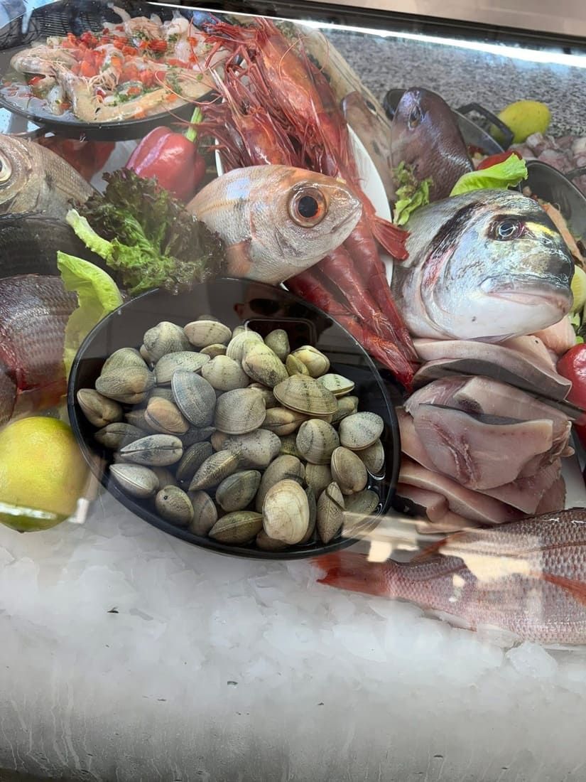 Exhibición de mariscos frescos con pescado, mariscos, langosta y camarones sobre hielo en un mercado.