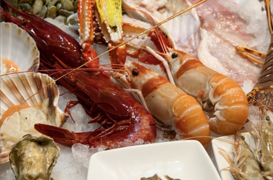 Surtido de mariscos sobre hielo, incluyendo mariscos y pescado rojo en un escaparate de mercado.