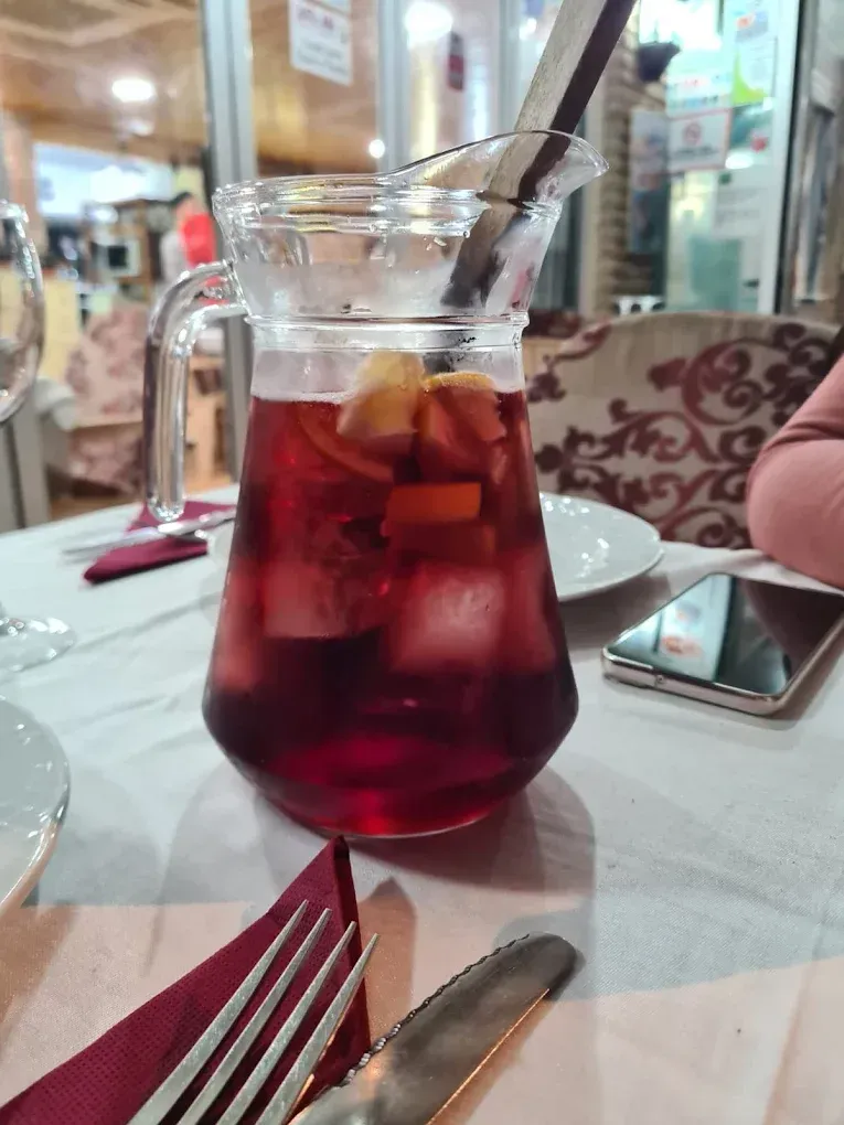 Jarra de sangría con fruta y hielo sobre una mesa en un restaurante.
