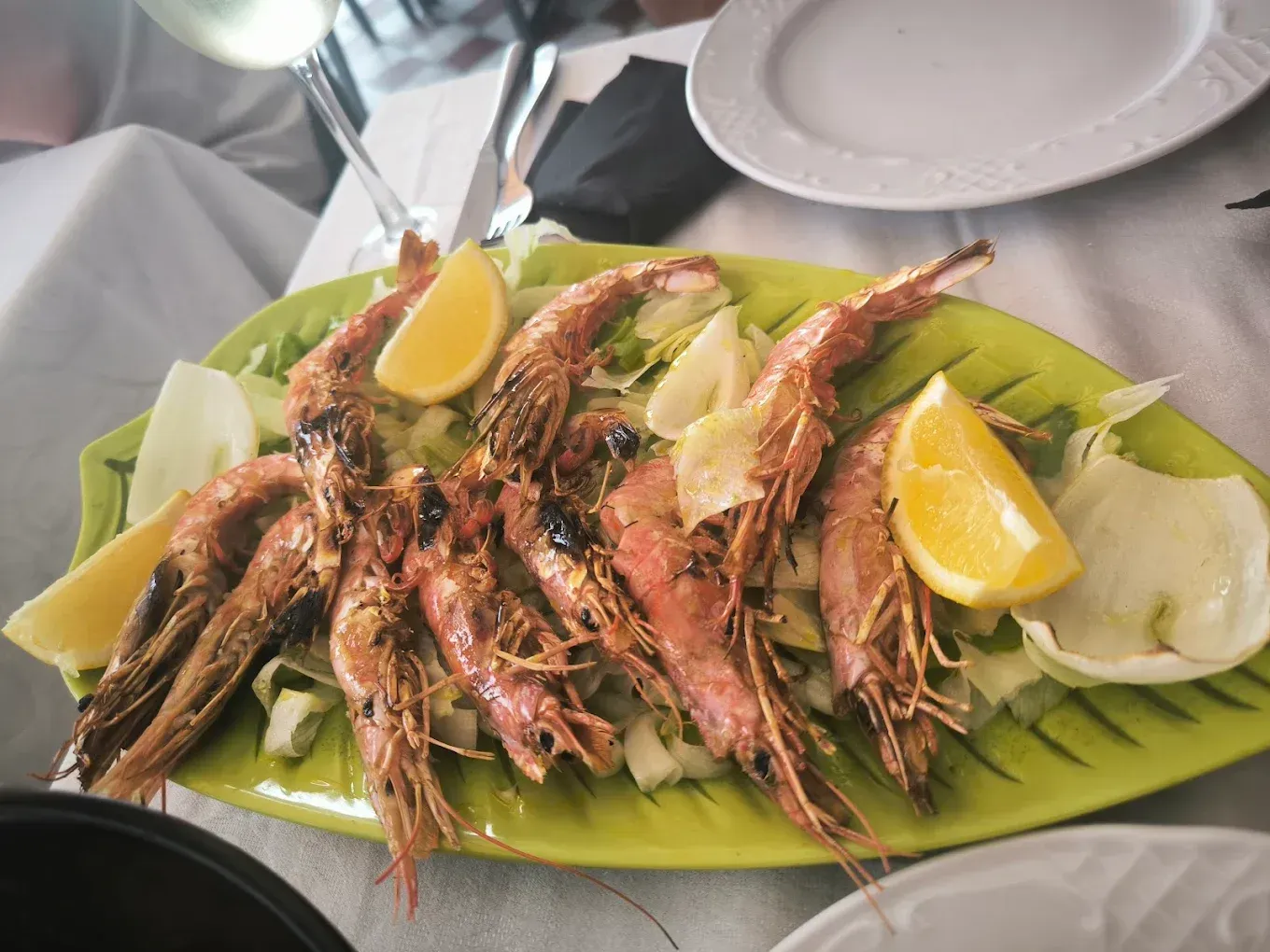 Ensalada de camarones con aguacate, rodajas de naranja y fresas en un plato blanco.