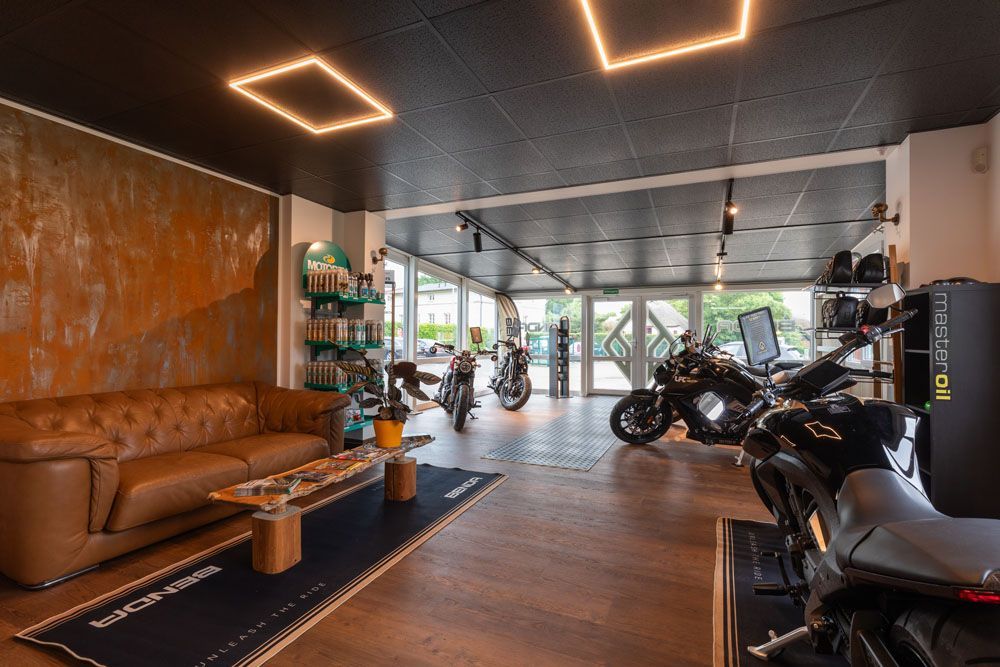 Moderner Motorrad-Showroom mit Ledersofa, Holzboden und ausgestellten Motorrädern.