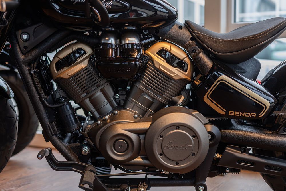 Nahaufnahme eines schwarz-bronzefarbenen Custom-Motorradmotors und einer Seitenverkleidung mit Totenkopfemblem