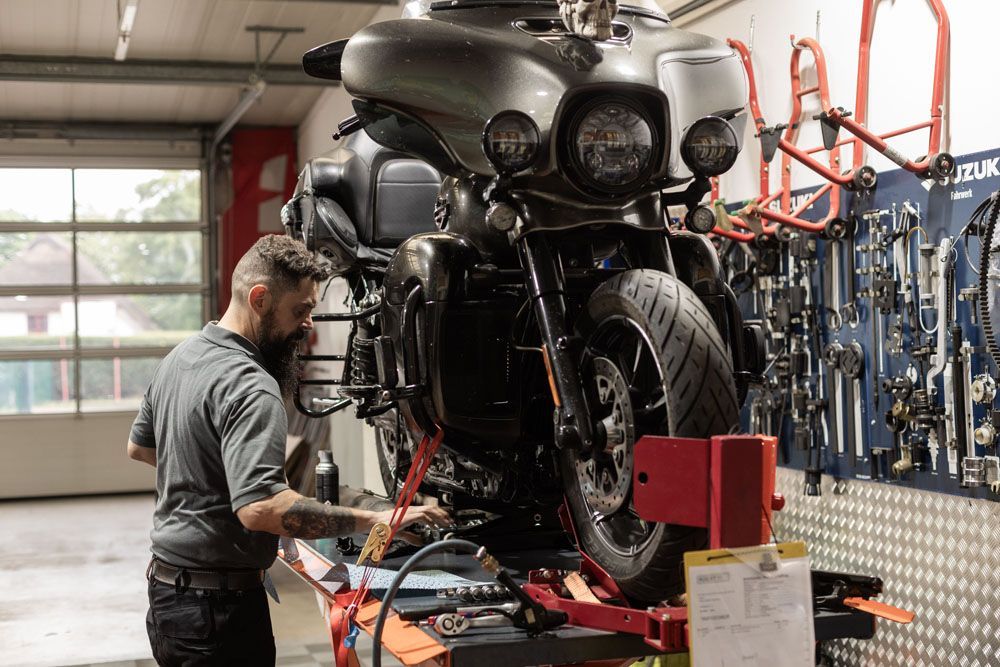Ein Mechaniker arbeitet in einer Werkstatt an einem großen Motorrad.