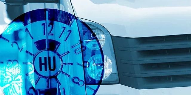 Blaue, uhrähnliche Abdeckung mit der Aufschrift „HU“ auf dem Kühlergrill eines Autos