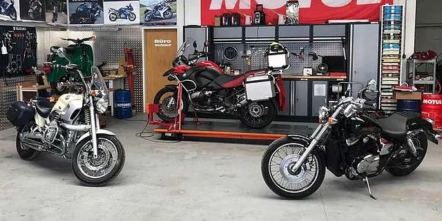 Innenansicht eines Motorradgeschäfts mit mehreren Motorrädern, darunter ein schwarzer Cruiser im Vordergrund und ein rotes Motorrad auf einer Hebebühne.