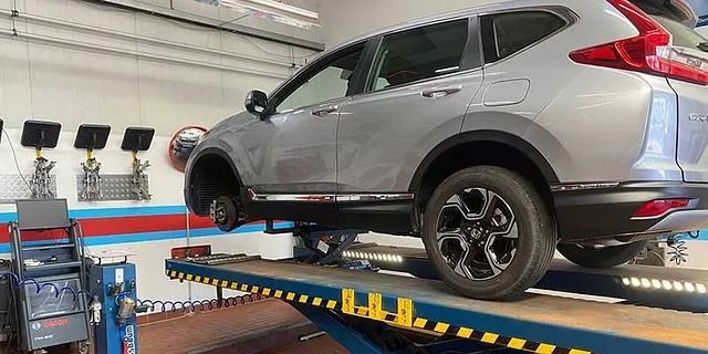 Silberner SUV auf einer Hebebühne in einer Autowerkstatt