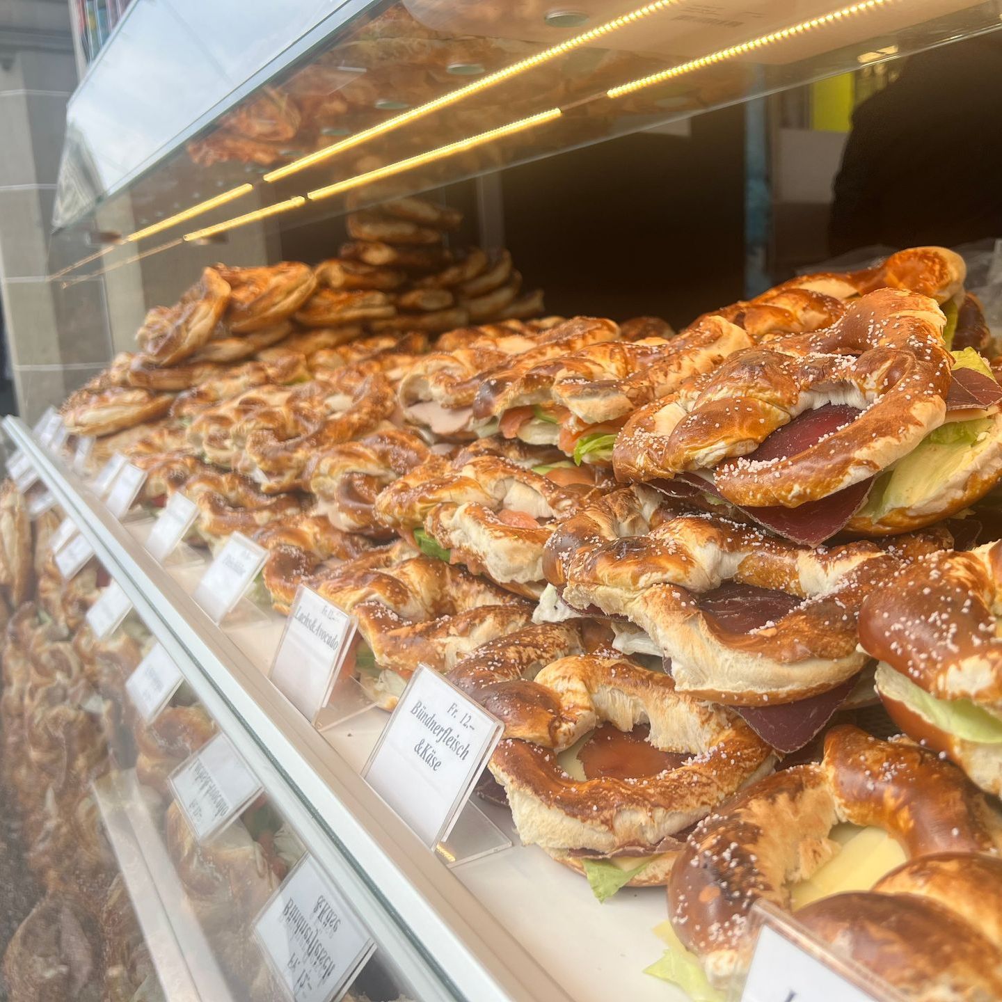 Zwei Sandwiches liegen auf einem weissen Teller auf einem Holztisch. Foto von der Victoria Brezelbäckerei AG