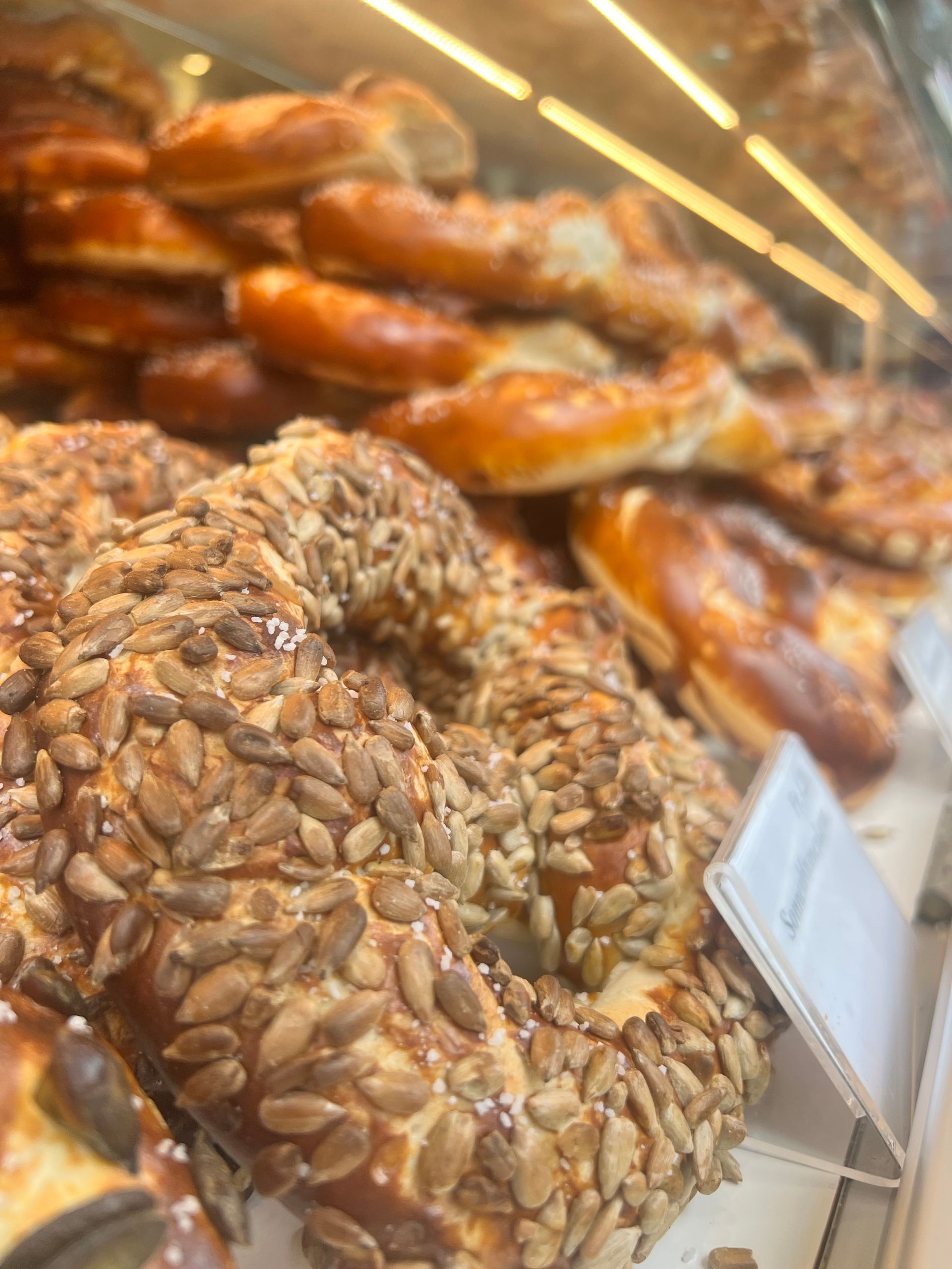 Eine Nahaufnahme einer Brezel mit Sonnenblumenkernen in der Vitrine einer Bäckerei.