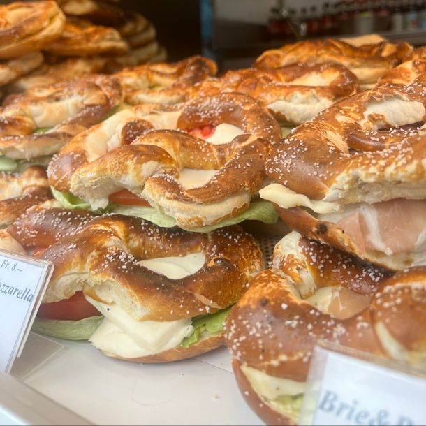 Eine Auslage mit Brezeln und Sandwiches auf einem Glasregal.
