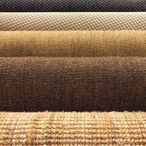 Close-up de amostras de carpete enroladas em tons de marrom, bege e cinza, exibindo várias texturas.