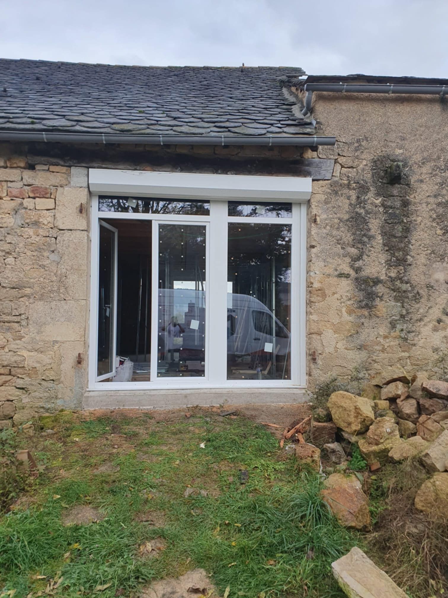 Grande porte vitrée avec volets roulants.