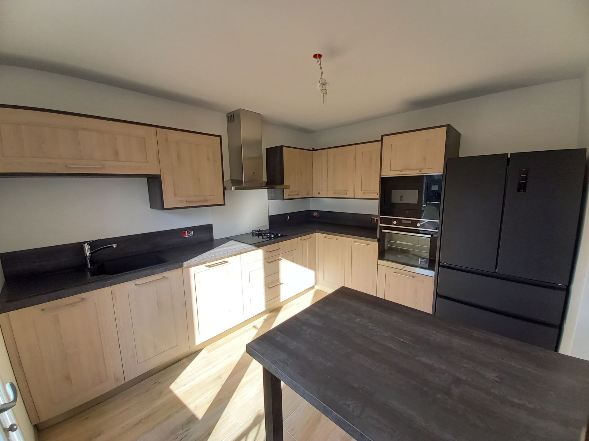 Cuisine en bois et plan de travail noir.