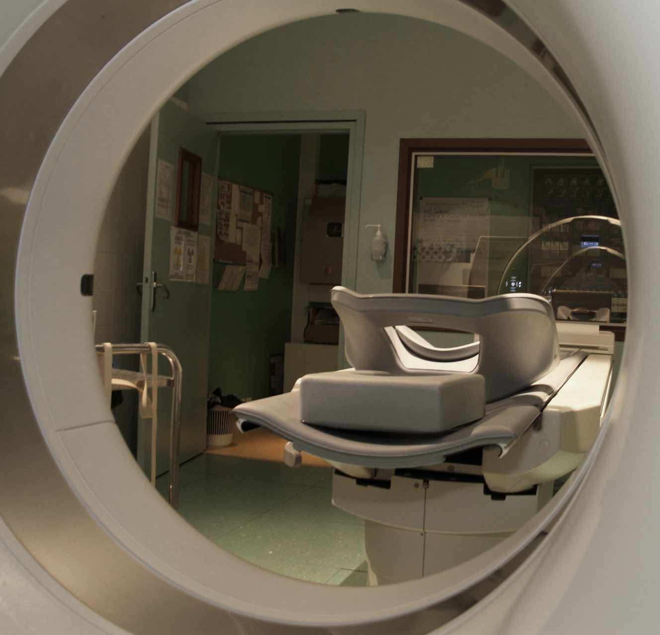 Salle d'examen dentaire vue à travers une ouverture circulaire, avec un fauteuil inclinable et des murs verts.