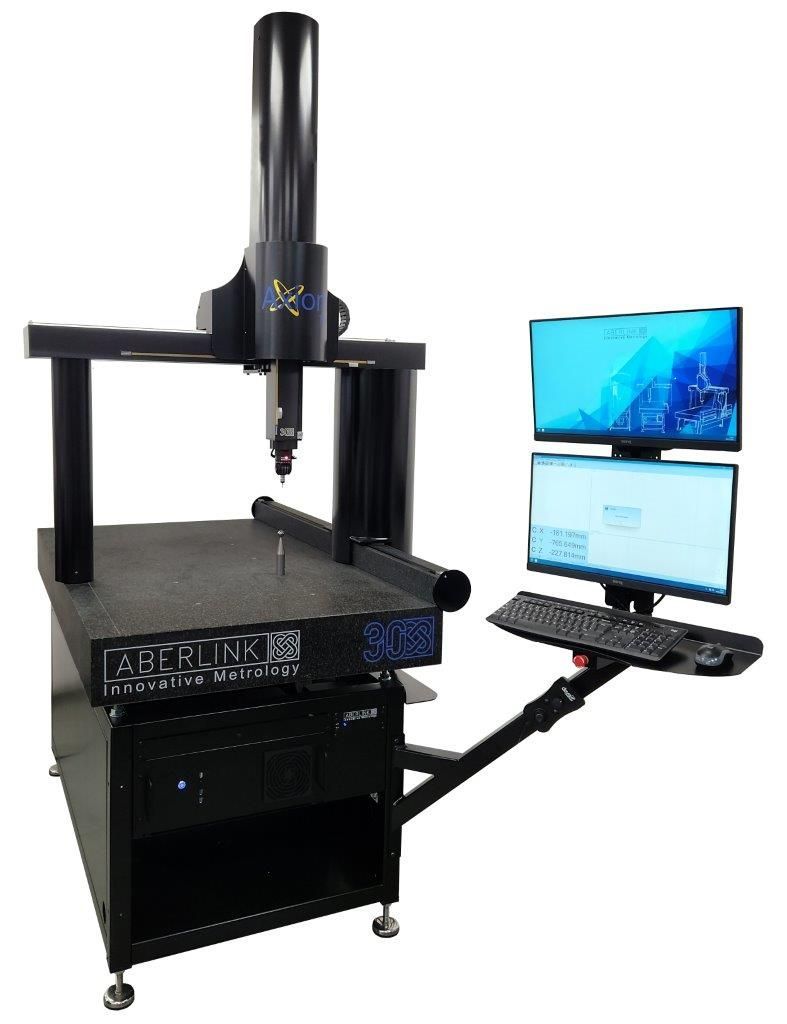 Una máquina está colocada encima de una mesa al lado de una computadora.