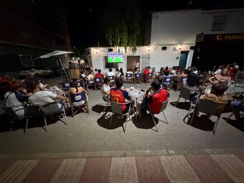Gente bailando en una discoteca con bebidas sobre las mesas y luces de colores en lo alto.