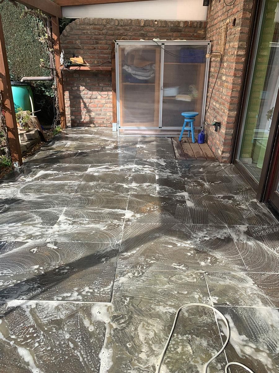 Eine Terrasse mit einer Glasschiebetür und einer Ziegelmauer.