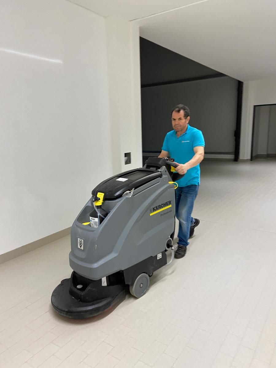 Ein Mann reinigt einen Boden mit einer Maschine.