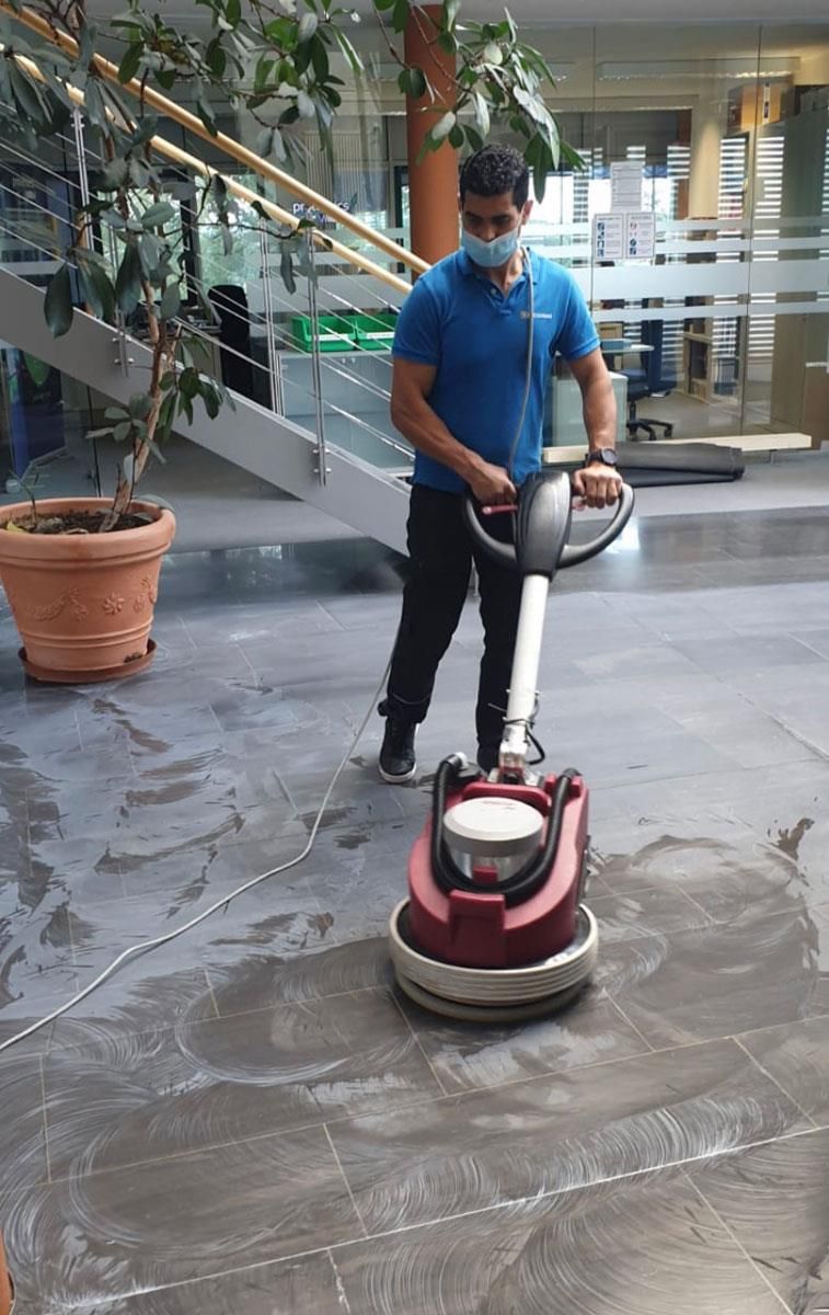 Ein Mann mit Maske benutzt eine Maschine zum Bodenwischen.