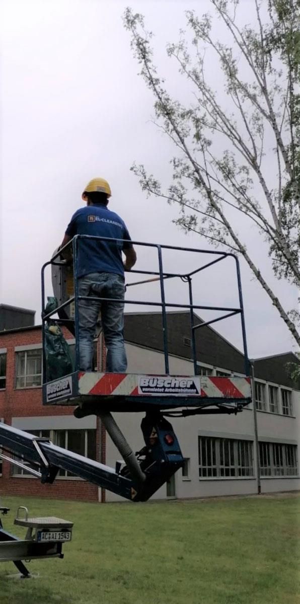 Ein Mann in einem blauen Hemd steht in einem Eimer auf einem Lift