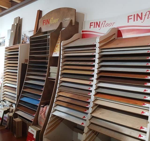 Muestras de pisos en exhibición en una tienda, mostrando varios colores y acabados de vetas de madera.