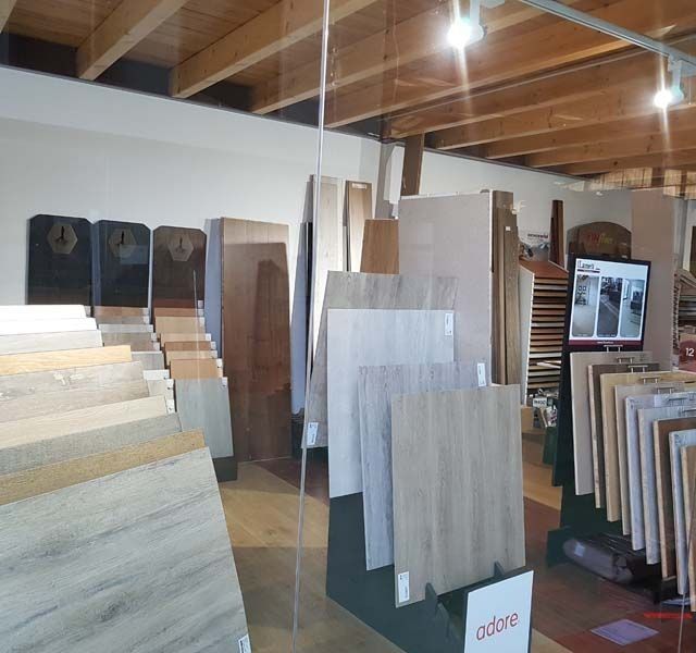 Sala de exposición de azulejos que muestra diversas muestras de pisos: azulejos con apariencia de madera, piedra y cerámica.