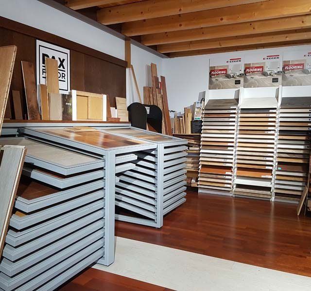 Una sala de exposición de pisos con muestras de madera expuestas en estanterías. Se ven los pisos de madera noble.