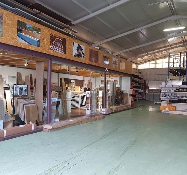 Interior de un taller de madera; una gran sala con madera, herramientas y maquinaria.